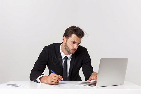 在办公室工作的英俊商人用笔记本电脑的前视线用笔记本电脑孤立的白人图片