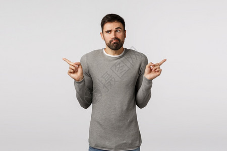 穿着灰色毛衣的不果断和无知英俊长胡子男冒着麻烦做出抉择有两个不同的选择在购物市场的产品中做出选择可怕的不确定指着侧面穿灰色毛衣的图片