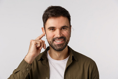 有吸引力的胡子现代男在城市行走的商人和通过无线耳机行走的客户用耳机打改变播放列表中的音量或歌曲微笑舒适和容易使用有吸引力的胡子现图片