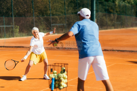 年长妇女与教员一起打网球图片