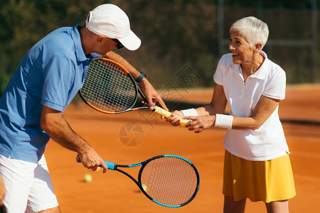 网球教官与60多岁高龄女同在粘土场上网球课图片