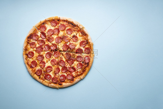 热辣椒尼比萨片切在上方的蓝色桌子美味的自制意大利菜披萨加热辣椒尼和莫扎里拉图片