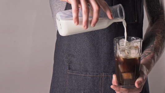 纹身咖啡师将新鲜牛奶倒到有冰块的玻璃上图片