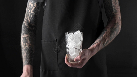 纹身咖啡师将有冰块的玻璃拿在手上图片