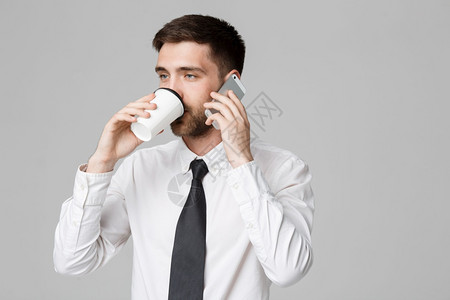 商业概念一个英俊的商人肖像戴眼镜拿着一杯咖啡和智能手机图片