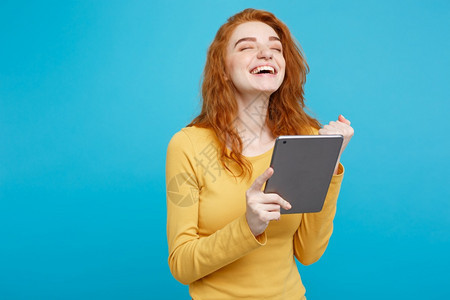 年轻美丽的红头发女孩在数字桌上快乐地微笑着玩弄一些东西蓝面纸背景复制空间图片