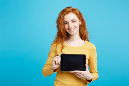 商业概念关闭肖像年轻美丽的有吸引力红头发女孩微笑着展示数字平板屏幕在黑色蓝的糊面背景图片
