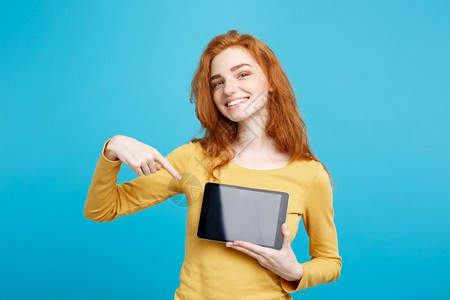 年轻美丽的红头发女孩微笑着展示数字平板屏幕在黑色蓝的面纸背景复制空间图片