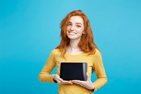 年轻美丽的红头发女孩微笑着展示数字平板屏幕在黑色蓝的面纸背景复制空间图片