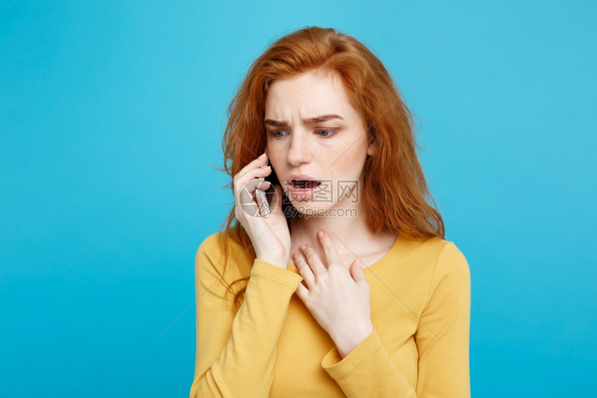 一位在黄色临时拨打手机被蓝色背景隔绝的疑惑女肖像图片