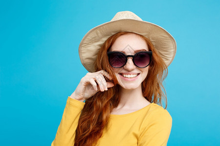 旅行概念关闭肖像年轻美丽的迷人姜红发女孩时髦的帽子和墨镜微笑蓝色的面部背景复制空间图片