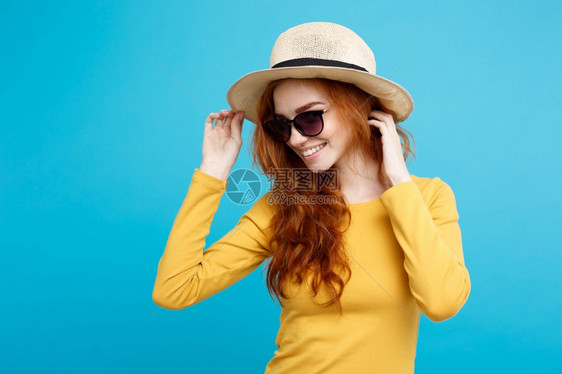 旅行概念关闭肖像年轻漂亮的红头发女孩wtih时尚帽子和墨镜微笑蓝色面部背景复制空间图片