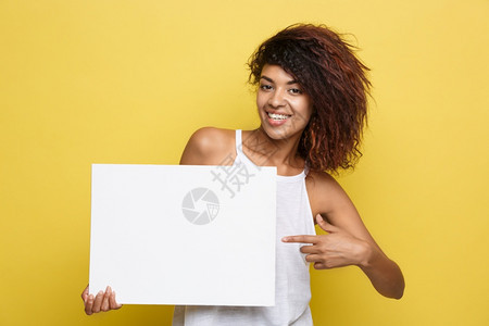 商业概念关闭肖像年轻美丽的有吸引力非裔美国人指向白的标志黄色面粉工作室背景复制空间指向白的标志图片