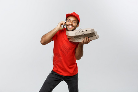 交付概念英俊的非洲比萨饼送货员与客户通电话的肖像与客户隔绝在灰色工作室背景上复制空间与灰色工作室背景上隔绝图片
