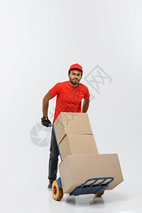 交付概念英俊的非洲送货员或运用一堆箱子推运手车的肖像在灰色工作室背景上隔离复制空间交付概念英俊的非洲送货员或运用一堆箱子推运手车图片