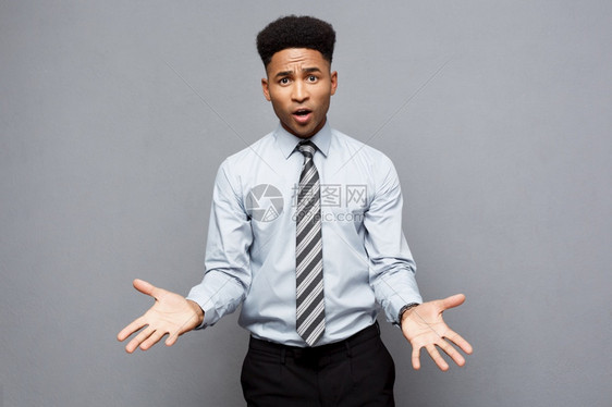 商业概念自信快乐的年轻非洲美国人在他面前举手表示对灰色背景的失望图片