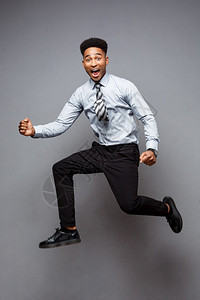 商业概念成功的非裔美国商人在办公室快乐跳跃的完整肖像图片