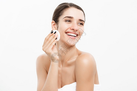 美容护肤概念美丽的妇女用棉布擦脸在白色背景和微笑下打扫脸部图片