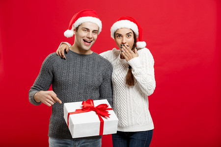 圣诞节概念圣诞节毛衣中的年轻夫妇肖像用手指表示礼物的势圣诞节毛衣中的年轻夫妇肖像用手指表示礼物的势图片