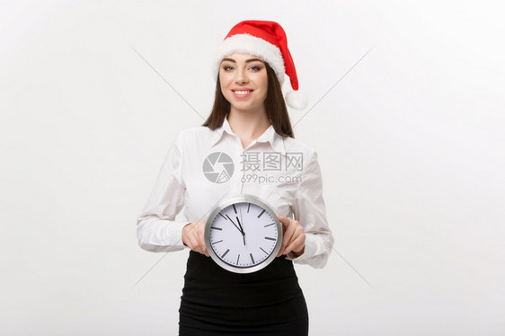 时间管理概念年轻快乐的女商人带着圣塔帽时钟与白种背景隔绝图片