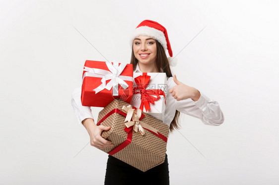 商业概念美丽的天主教青年女商人戴着圣塔帽拿许多礼品盒露出大笑图片