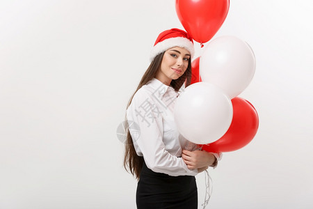 商业概念美丽的年轻有自信女商人戴着圣塔帽子拿气球庆祝圣诞节图片