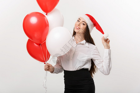 商业概念美丽的年轻有自信女商人戴着圣塔帽子拿气球庆祝圣诞节图片