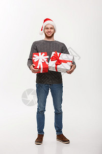 圣诞概念带着胡子的快乐年轻人带着许多礼物与白色背景隔绝图片