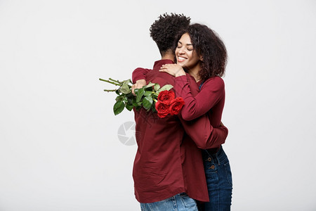 年轻的非洲情侣拿着玫瑰花拥抱图片