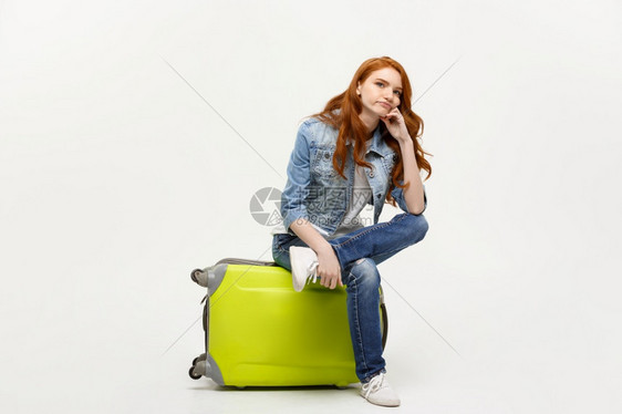 旅行和生活方式概念年轻红发妇女坐在一个包里面部表情无聊与黄色背景隔绝旅行和生活方式概念年轻红发妇女坐在一个包里面部表情闷与黄色背图片