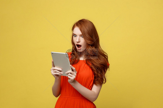 技术和生活方式概念令人惊讶的是身着橙色衣服的年轻女身着黄色鲜白背景技术和生活方式概念身着橙色衣服的年轻女身着橙色衣服的惊人年轻女图片