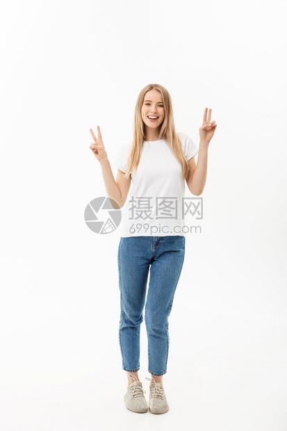 一位快乐的年轻女完整肖像站立并展示和平的姿态两只手隔在白色背景上一位快乐的年轻女完整肖像两只手隔在白色背景上图片