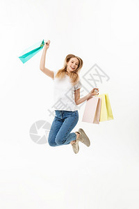 一个快乐的漂亮女孩拿着购物袋跳看镜头孤立在白色背景上一个快乐的漂亮女孩拿着购物袋跳看镜头图片