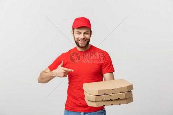 交付概念英俊的causin比萨饼送货员用手指着孤立于灰色背景交付概念英俊的causin比萨送货员用手指着图片