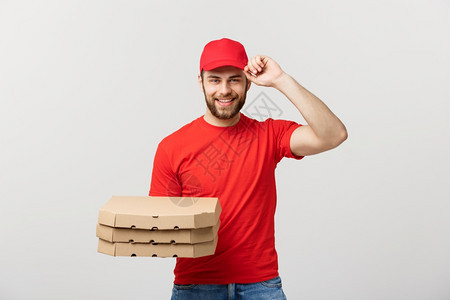 交付概念英俊的披萨送货员穿红色制服帽子拿着披萨盒孤立在白色上图片