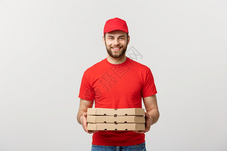 快乐的年轻送货员拿着比萨饼盒却与白人工作室背景隔绝图片