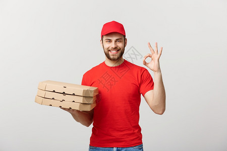 交付概念英俊的比萨饼送货员在灰色背景上打好信号图片