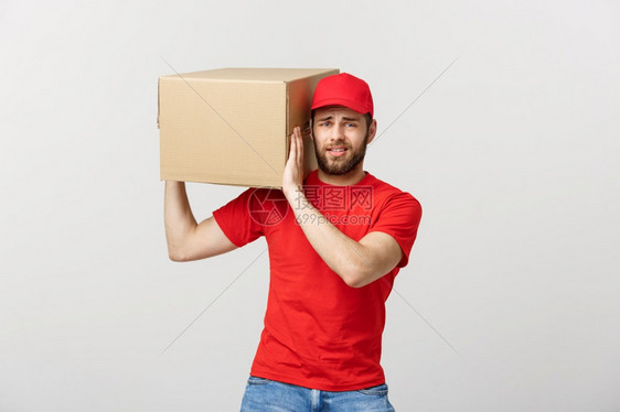 交付概念英俊的送货员带箱子忧心的员面部表情孤立的灰色背景忧心的面部表情孤立的灰色背景图片