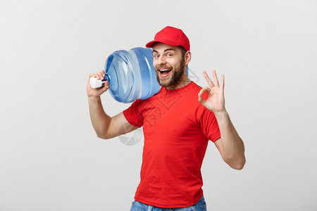 装着红色t恤衫和帽子的装满新鲜饮料瓶装送水员并在白色背景上露出笑脸的瓶装送水员图片