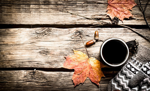 秋天风格一杯带手套的热咖啡放在木制桌子上图片