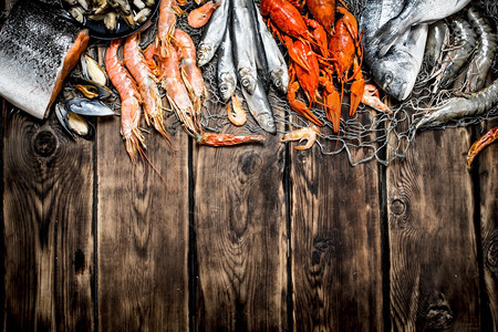 新鲜生海产食品渔网上的各种海产食品木质背景的海产食品渔网上的多种海产食品图片