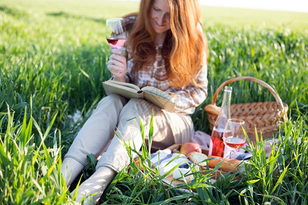 女孩在野餐篮和面包店附近喝着一杯酒和书的女孩图片