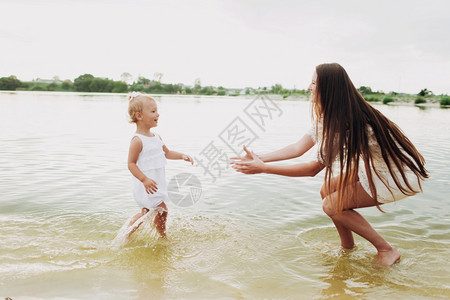 美丽的母亲与女儿在湖边玩耍暑假的概念母亲和婴儿一起度过时间家庭阳光照选择关注美丽的母亲与女儿在一起玩乐湖边耍母亲和白天一起度过时图片