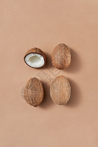 从三个成熟的全椰子和半个浅棕色背景的椰子中提取新鲜水果上面有柔软的阴影复制空间素食物概念浅棕色背景的新鲜成熟椰子果图片