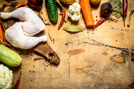 生鸡腿和煮汤蔬菜放在木制桌上生鸡腿和煮汤蔬菜图片