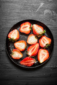 草莓一半在旧板子上黑木桌图片