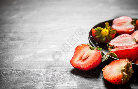 草莓一半在旧板子上黑木桌图片