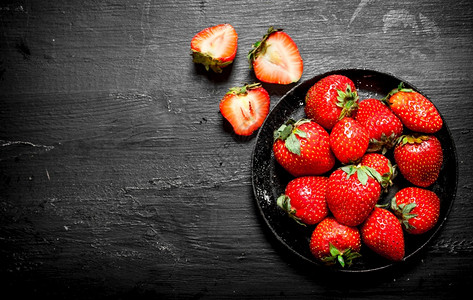 成熟的草莓旧盘子在黑木板上成熟的草莓旧盘子图片