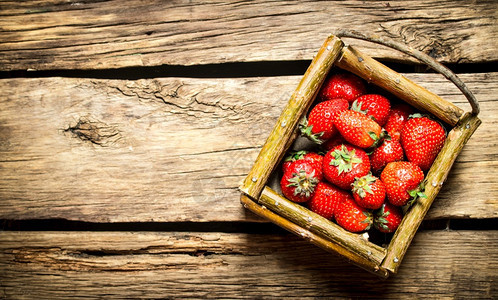 草莓放在篮子里木制桌子上图片