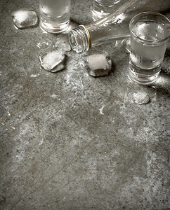 一瓶伏特加杯子和冰放在石板上图片